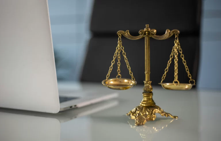 a golden balance scale beside a laptop