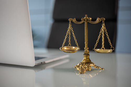 A golden weighing scale next to a laptop