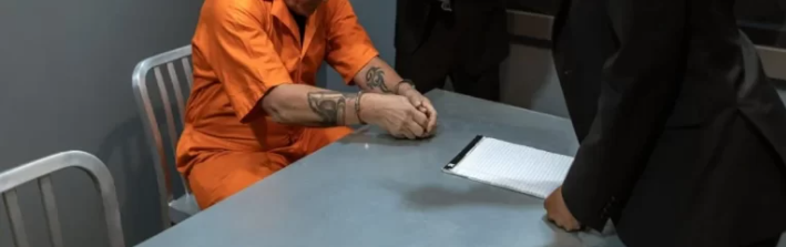  A person sitting on a table handcuffed. 