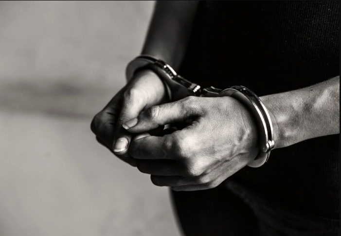 A person wearing handcuffs on their hands.