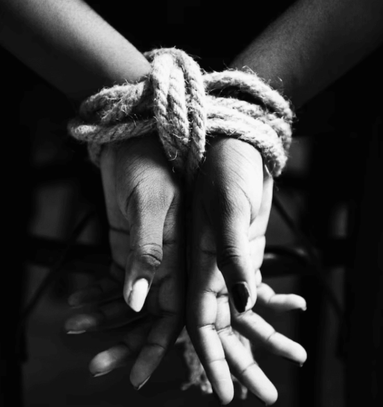 A person being tied up on a chair. 
