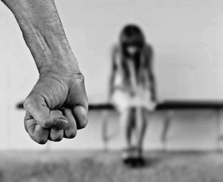 Close-up of a fist with a woman in the background.