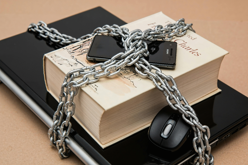 A photo showing a laptop, book, and smartphone locked in a chain