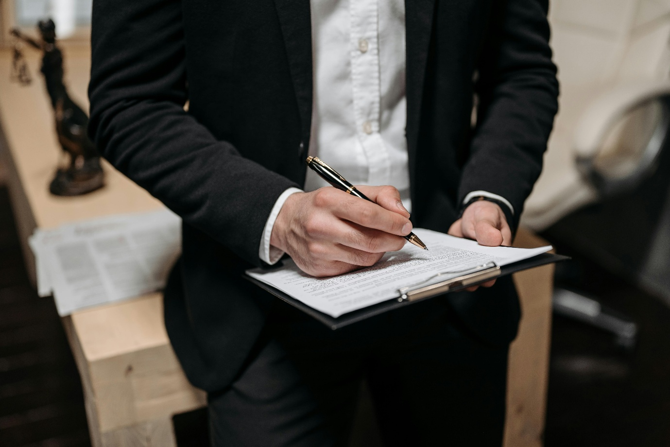 A photo showing a person holding a pen and a clipboard