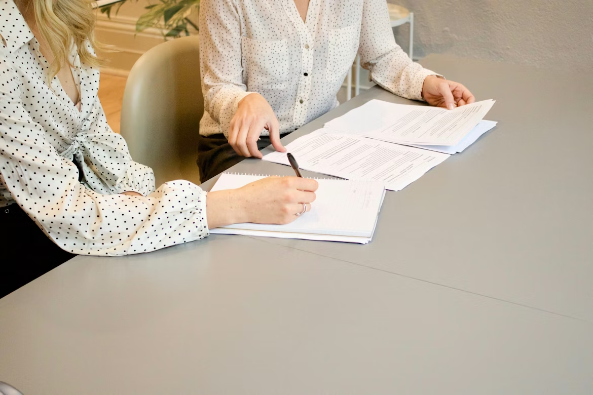 Person signing a document while another observes