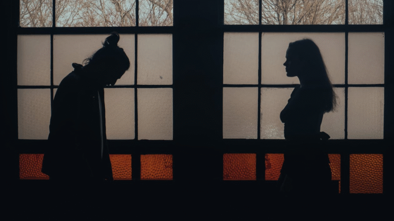 A couple standing at a distance from one another in a dark room
